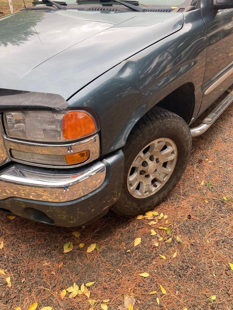 A gray truck is parked on a dirt road.