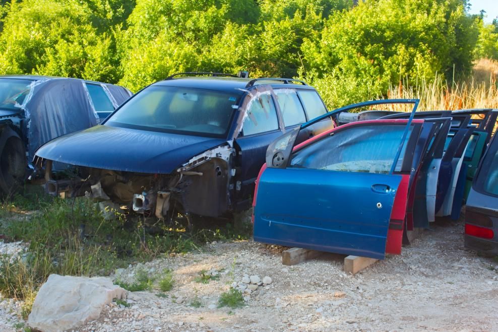 A Blue Car in A Junkyard and Several Doors — Jap Performance T/A All Tuggerah City Auto Dismantlers in Woy Woy, NSW