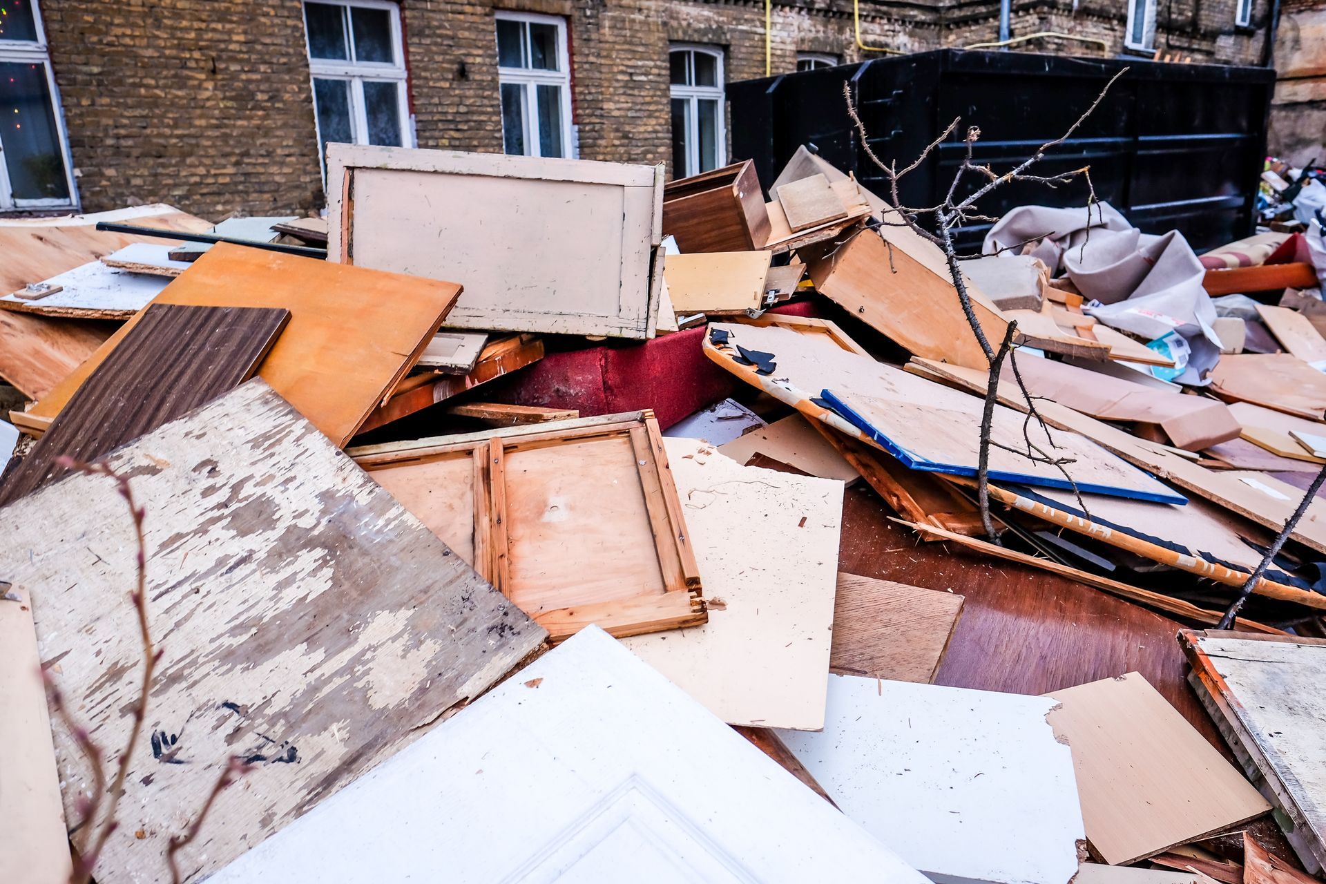 Piled construction debris and broken boards scattered in front of a brick building