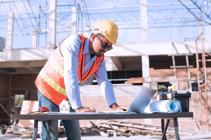 person wearing hard hat and looking at blueprints at construction site