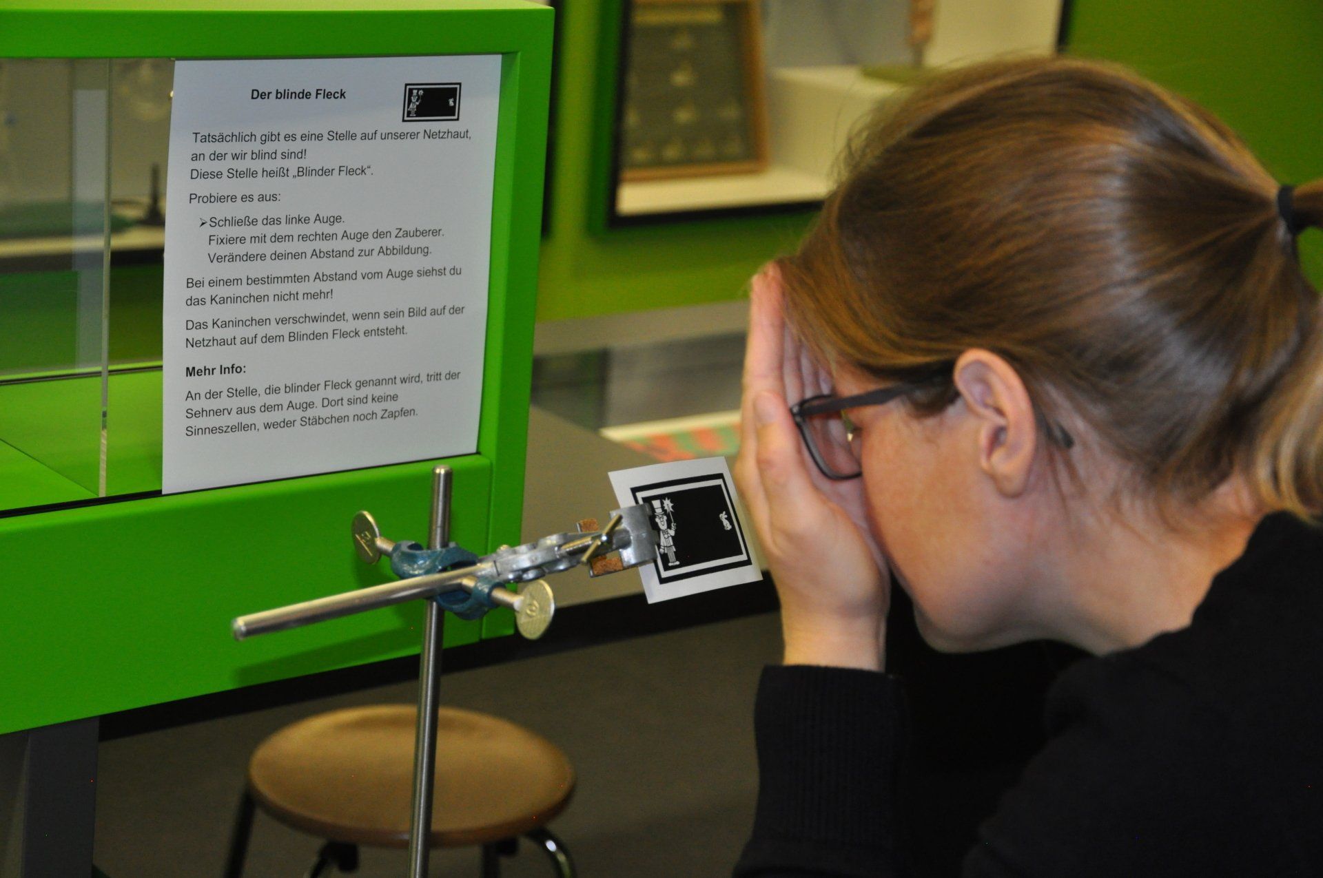 eine Person hält sich ein Auge zu und schaut auf eine Grafik eines Zauberers und eines Kaninchens