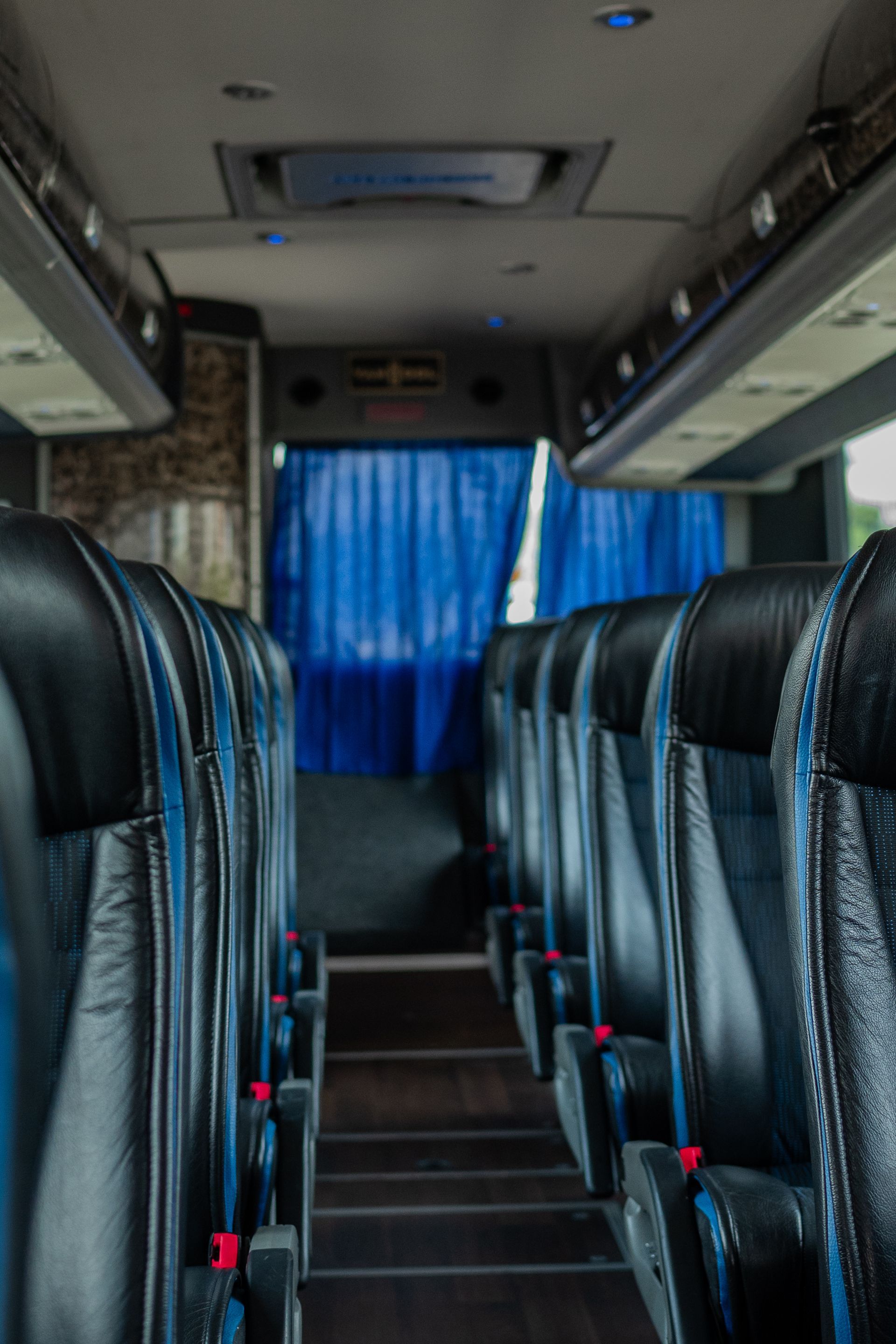 the inside of premier's bus with blue curtains and black seats