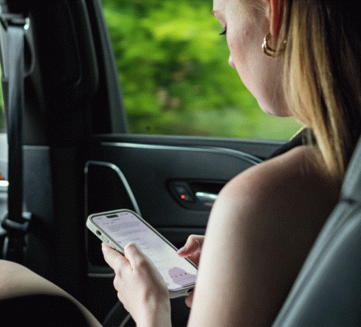 a woman is sitting in the back seat of a car looking at her cell phone