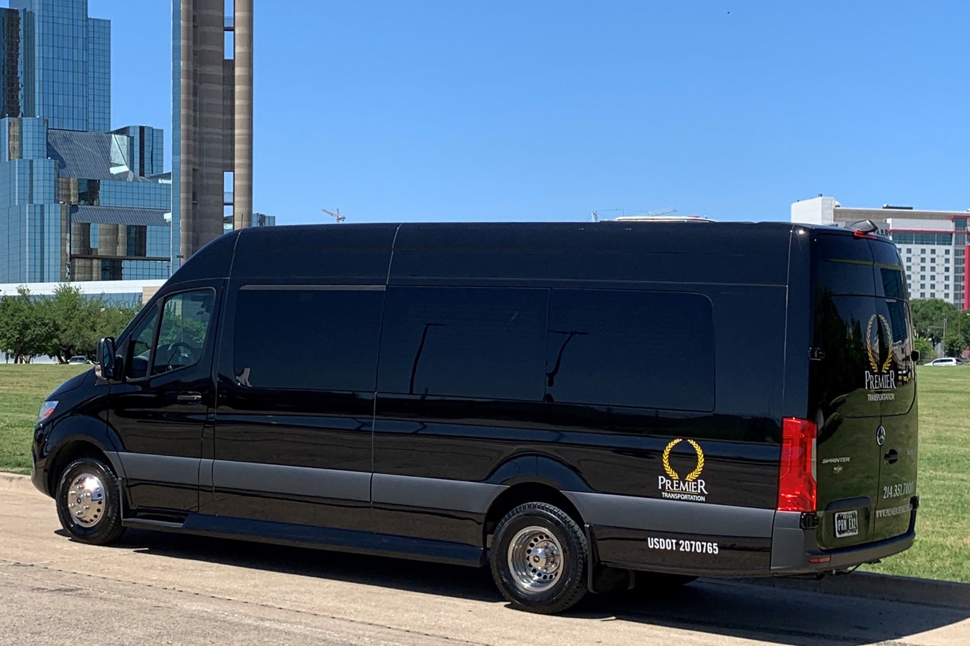 premier's black van is parked on the side of the road in front of a tall building .