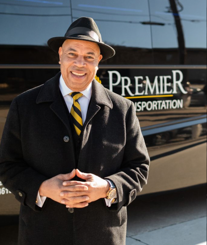a man standing in front of a premier transportation bus