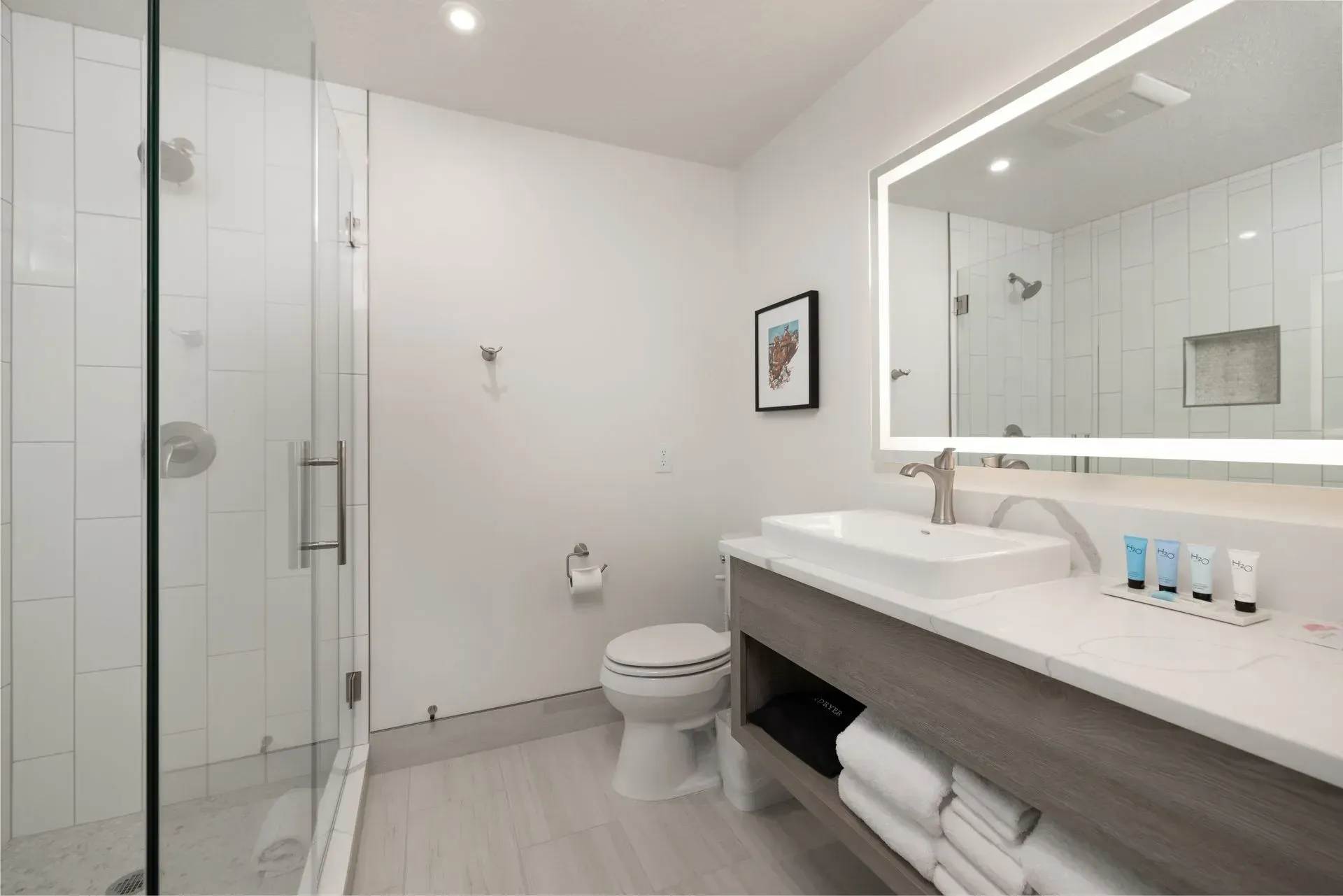 A bathroom in a hotel room with a toilet , sink and shower.