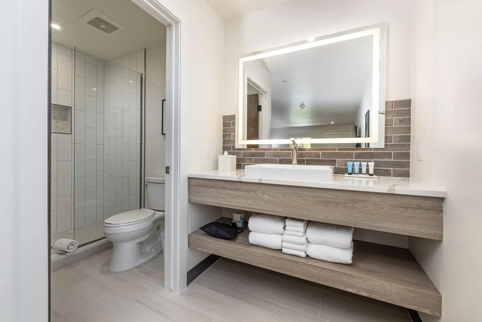 A bathroom with a toilet , sink , mirror and towels.