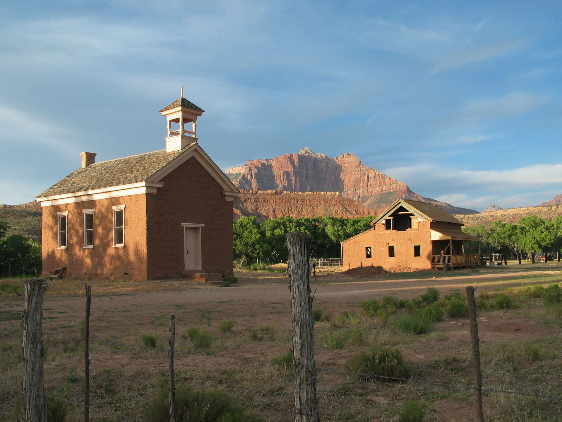 A brick building with a bell tower and a mountain in the background