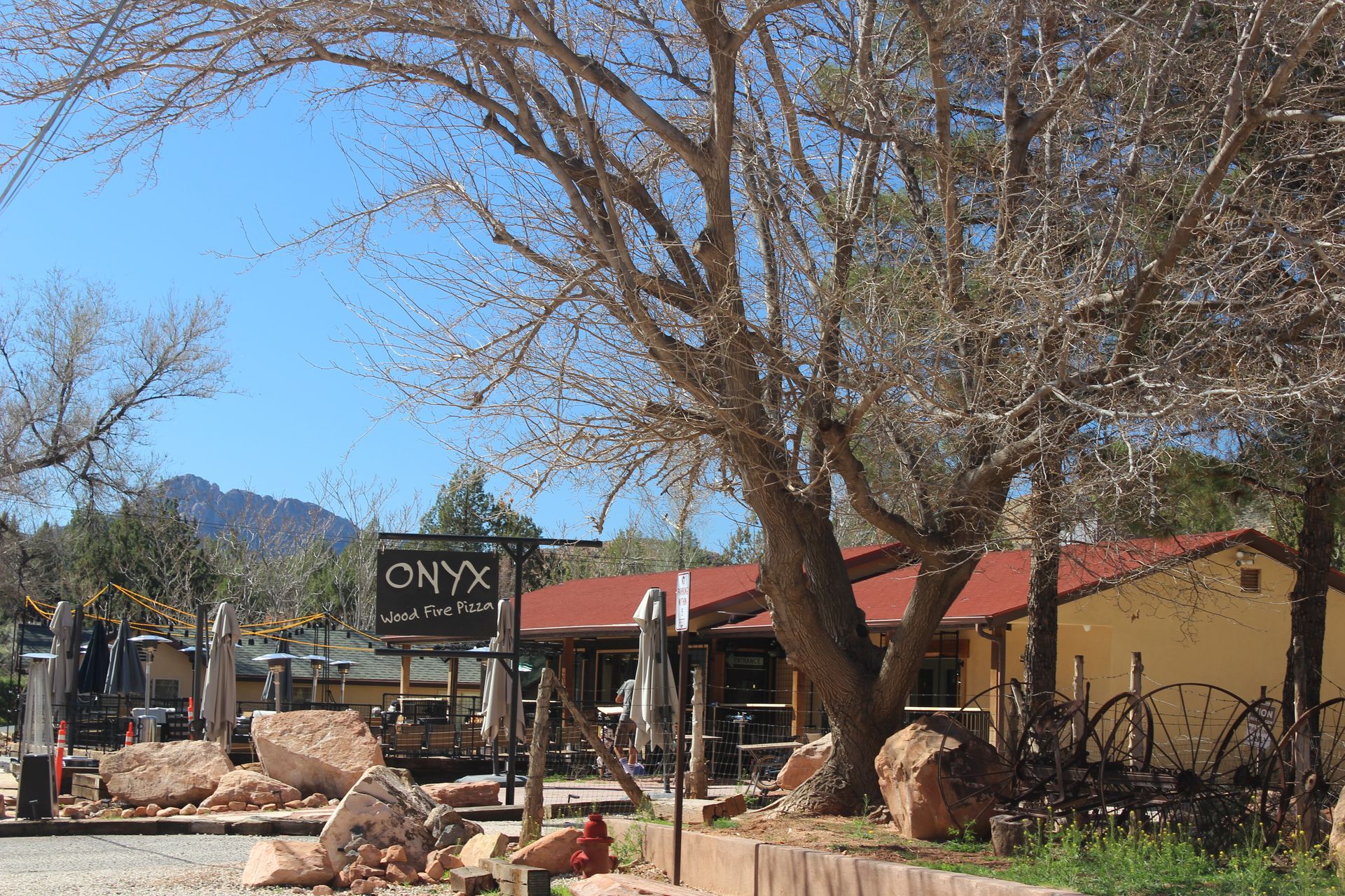 A building with a mountain in the background is surrounded by rocks and umbrellas.