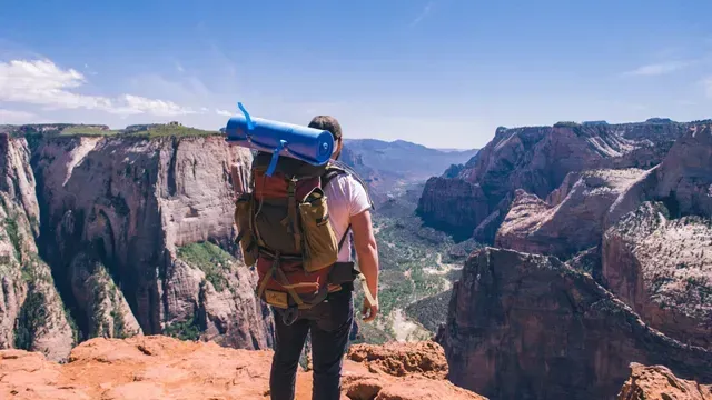 A person with a backpack is standing on top of a mountain.