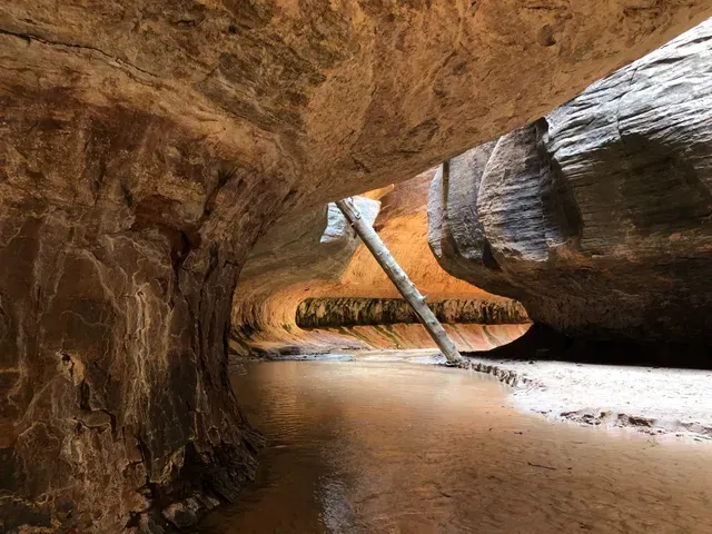 A narrow cave filled with rocks and water.