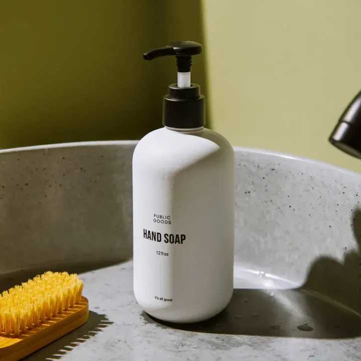 A bottle of hand soap is sitting on a sink next to a brush