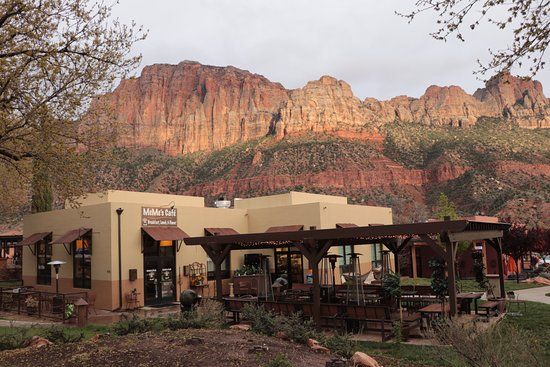 A building with a pergola in front of a mountain.