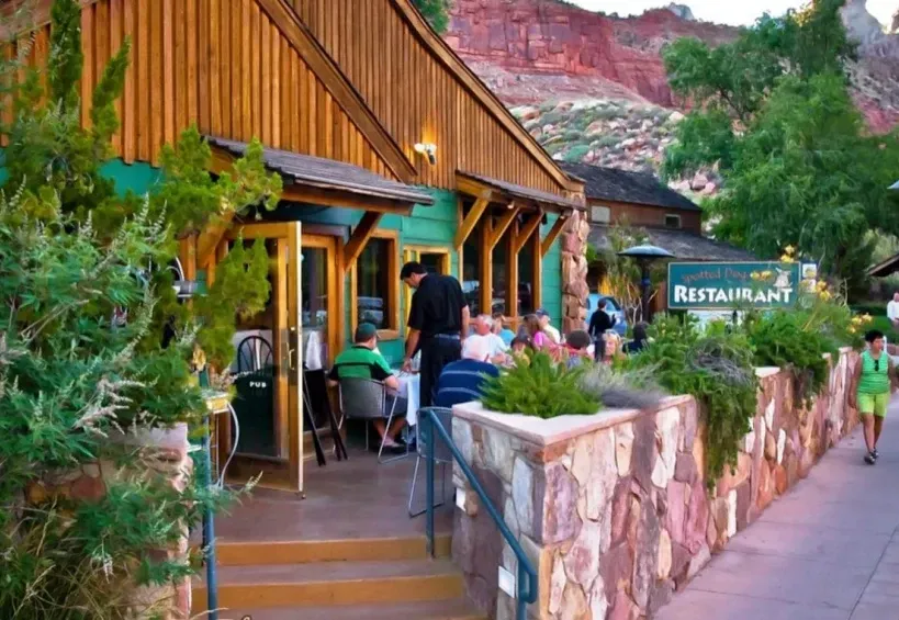 A group of people are sitting at tables outside of a restaurant.