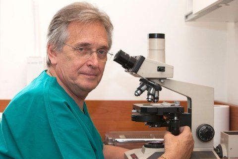 Un uomo in camice verde usa un microscopio in un laboratorio.