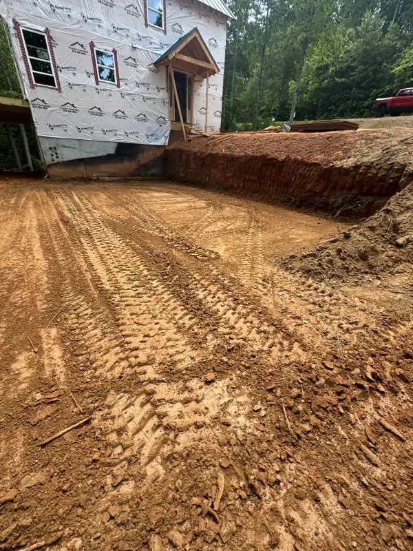 Construction site: Excavated area with tire tracks in front of a house under construction.
