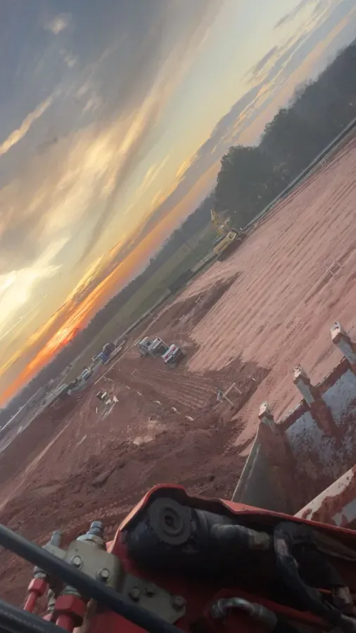 A red machine on a construction site with a sunset backdrop.