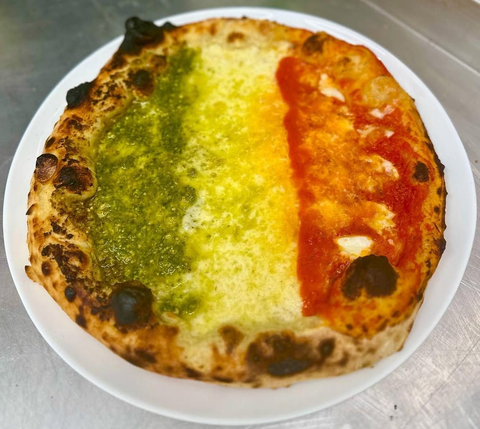 Pizza su un piatto bianco, condita con salsa verde, gialla e rossa in tre sezioni verticali.