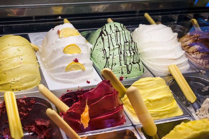Espositore di gelato colorato con gusti assortiti: giallo, bianco, verde, rosso e viola.