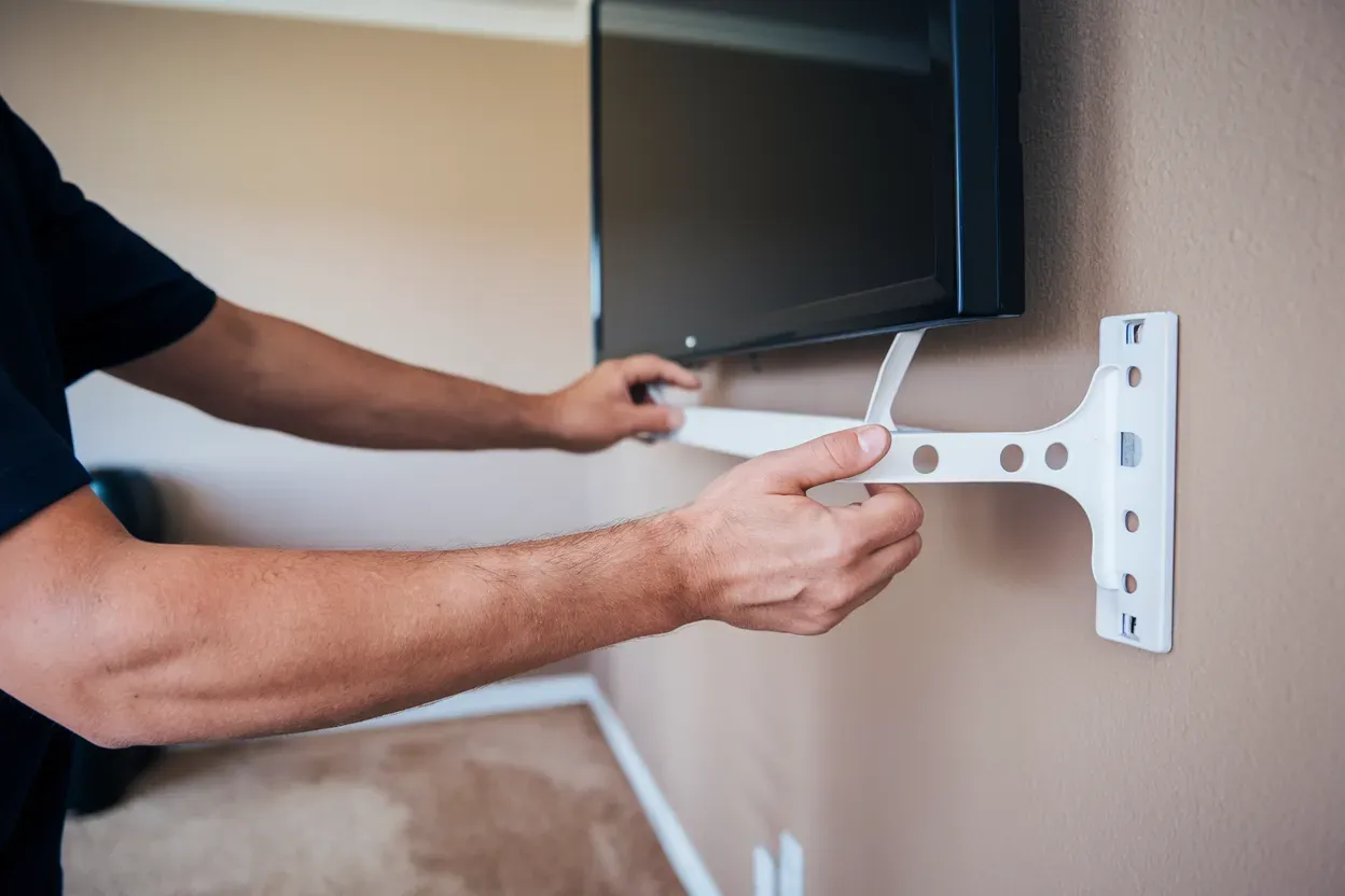 A man is installing a flat screen tv on a wall.