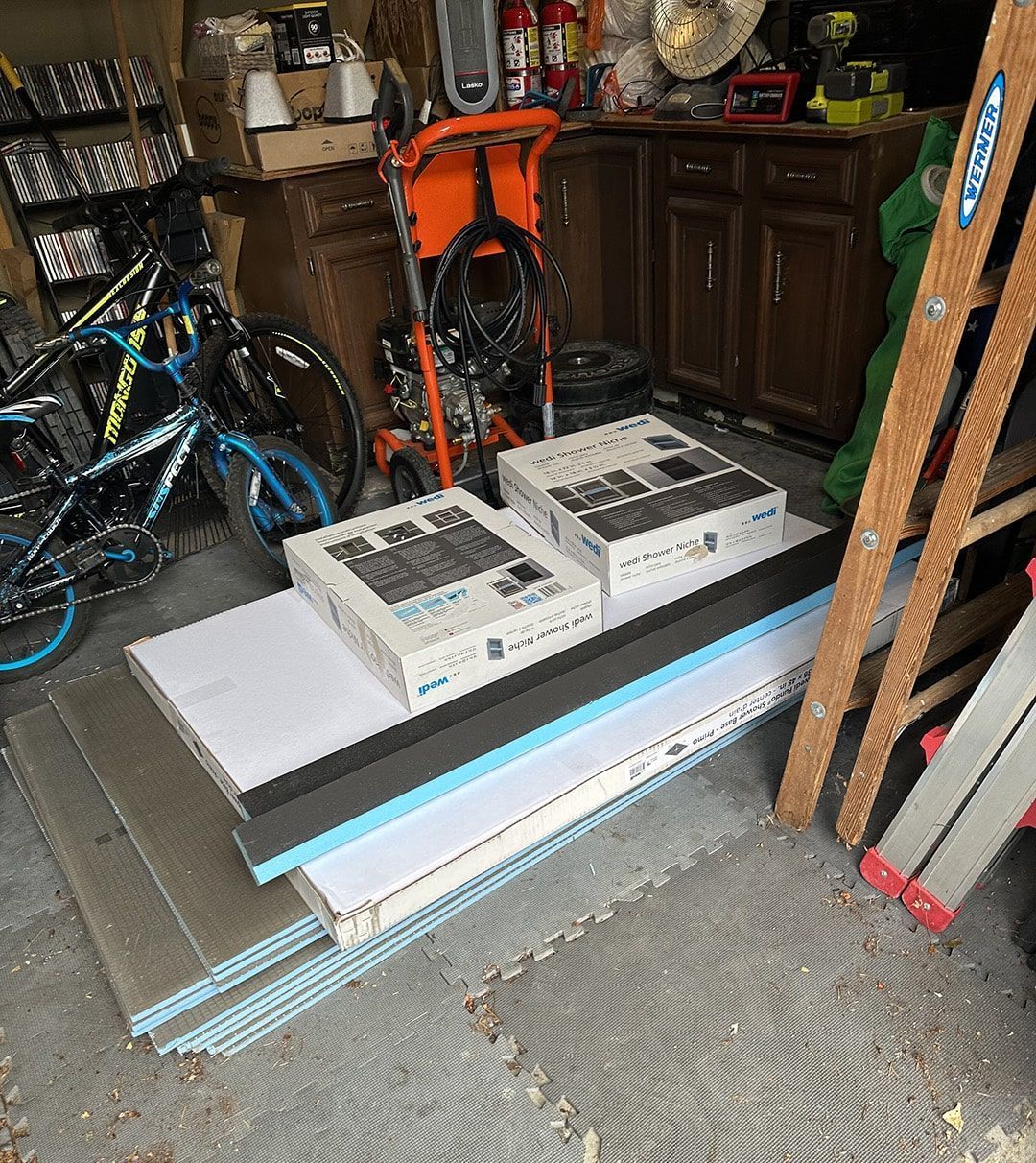 A bicycle is parked in a garage next to boxes and a ladder.