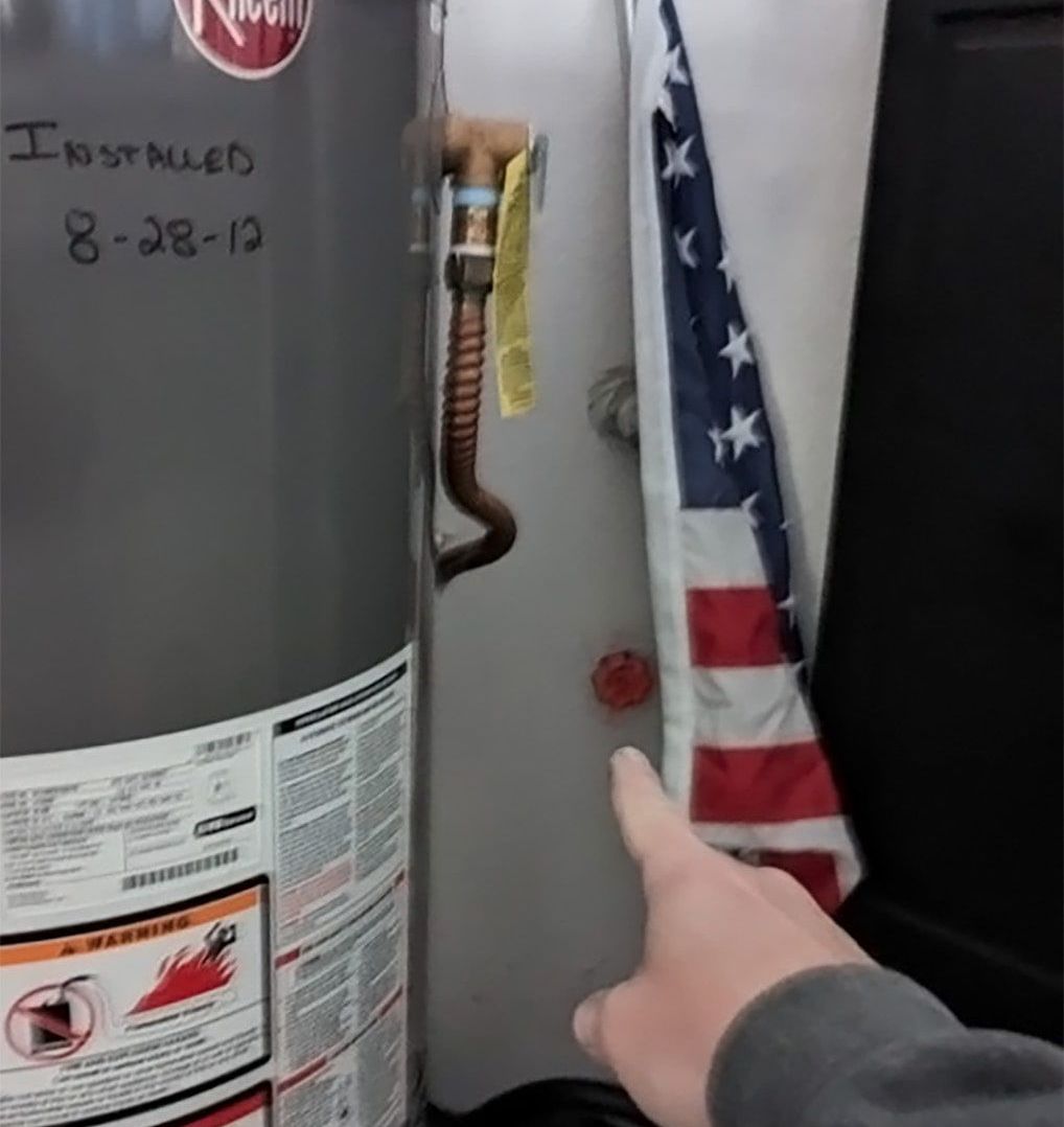 A person pointing at a hoover water heater that was installed on 8-28-13