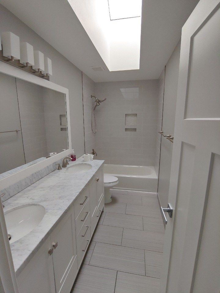 Contemporary tile bathroom white tiles, sleek tub, glass shower.
