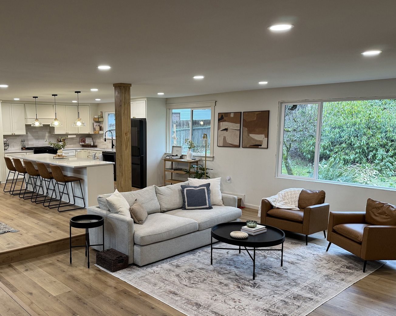 Spacious living room with a couch, armchairs, a rug, and an open kitchen.