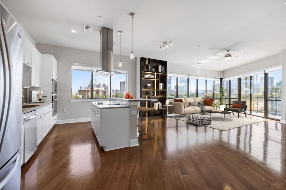 A kitchen and living room in a large apartment with hardwood floors at Water's Edge.