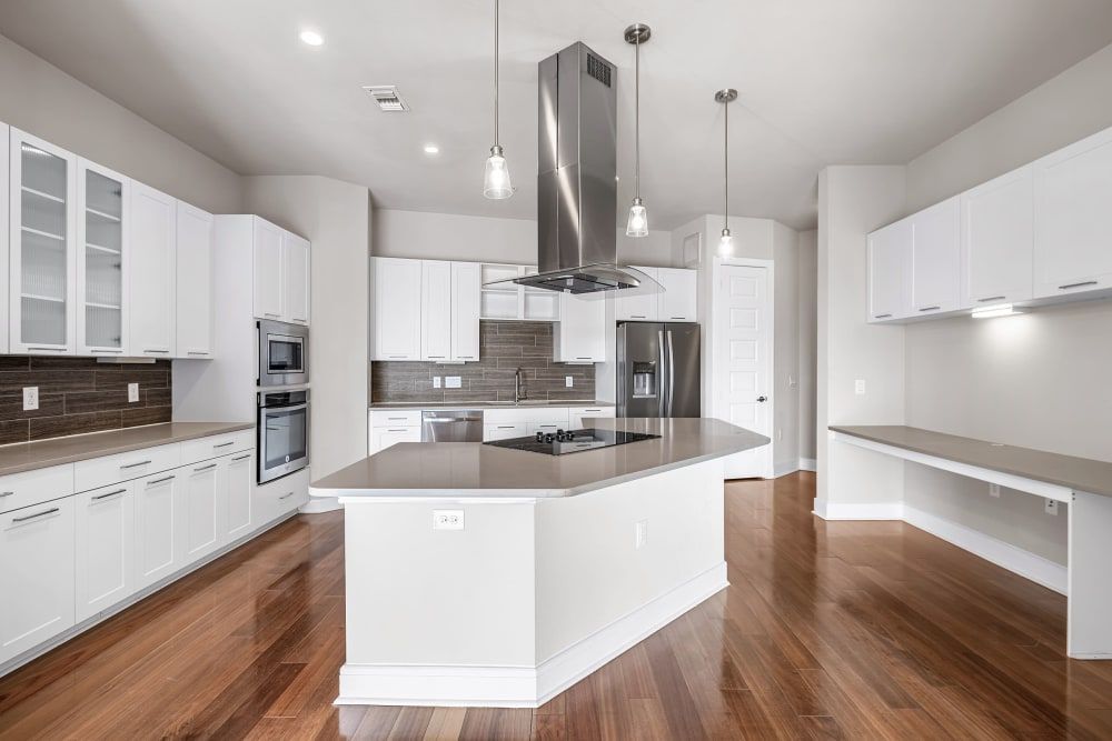 An empty kitchen with white cabinets and hardwood floors at Water's Edge.