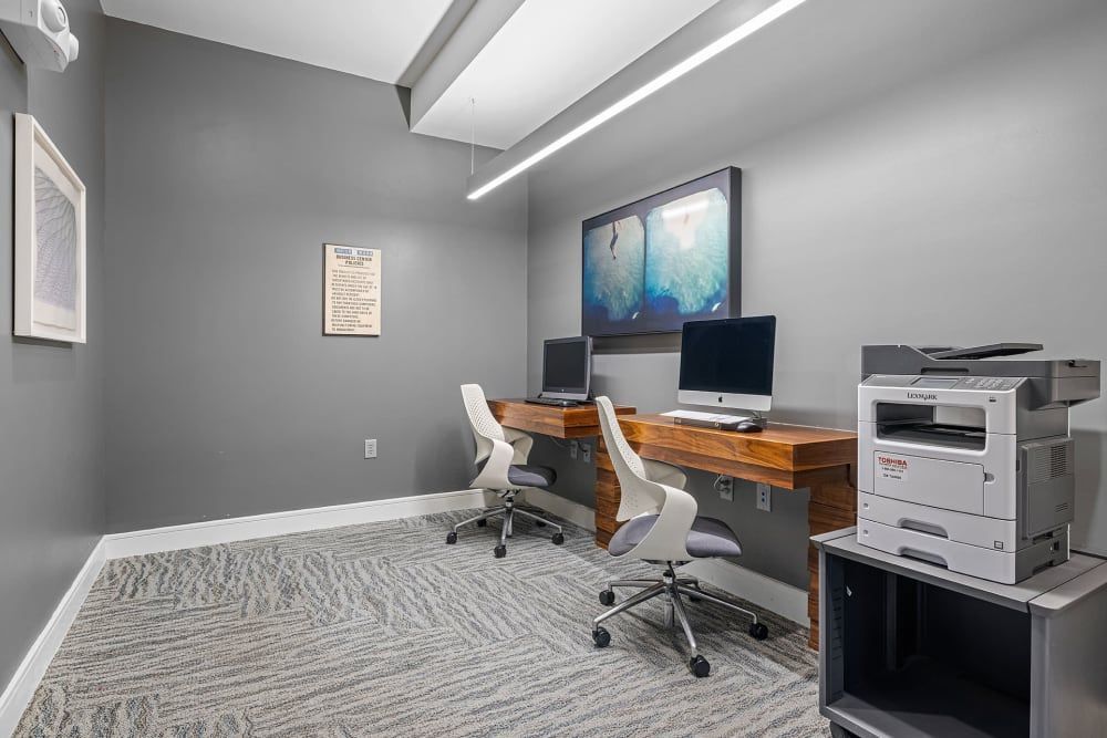 A room with two desks , chairs , computers and a printer at Water's Edge.