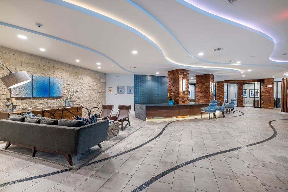 A large lobby with a couch , chairs , and a counter at Water's Edge.