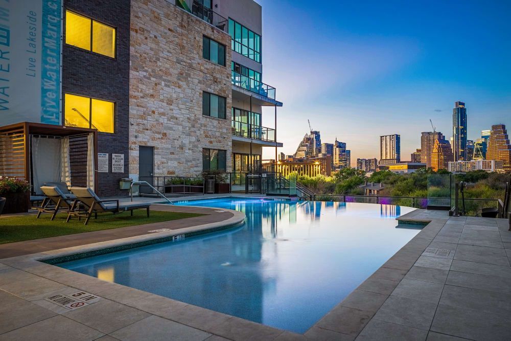 A large swimming pool in front of a building with a city skyline in the background  at Water's Edge.