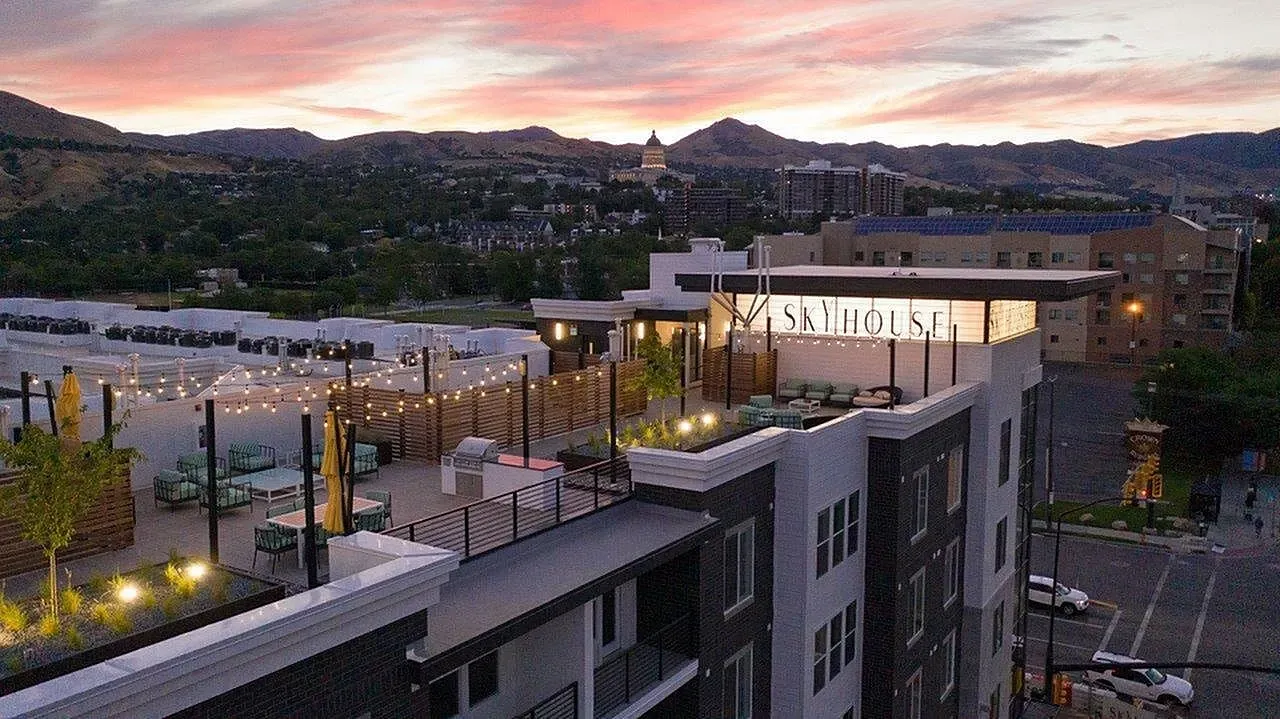 Sky House apartment building rooftop with seating, string lights, and mountain views at sunset.