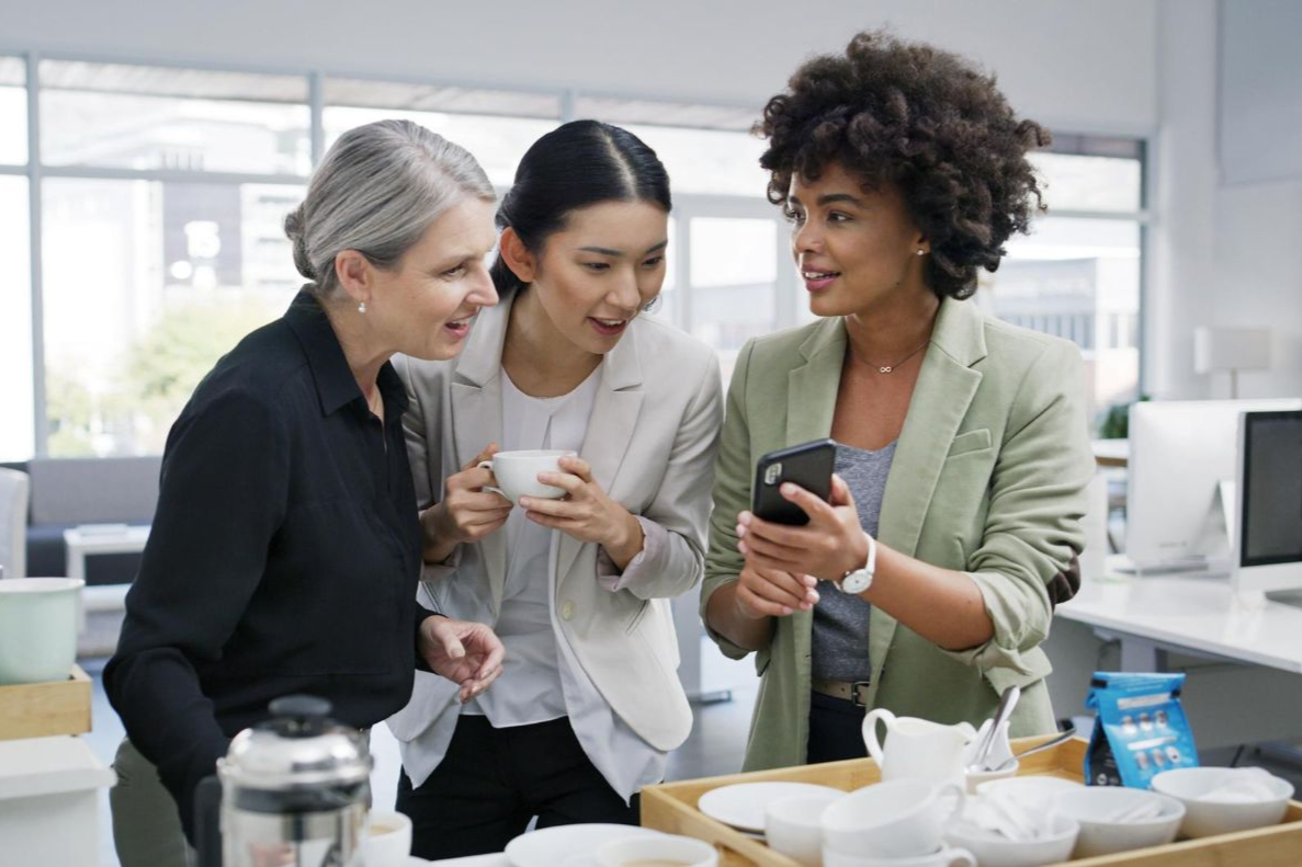 Three office workers looking at a mobile phone