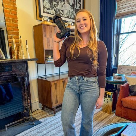 A woman is holding a camera in a living room