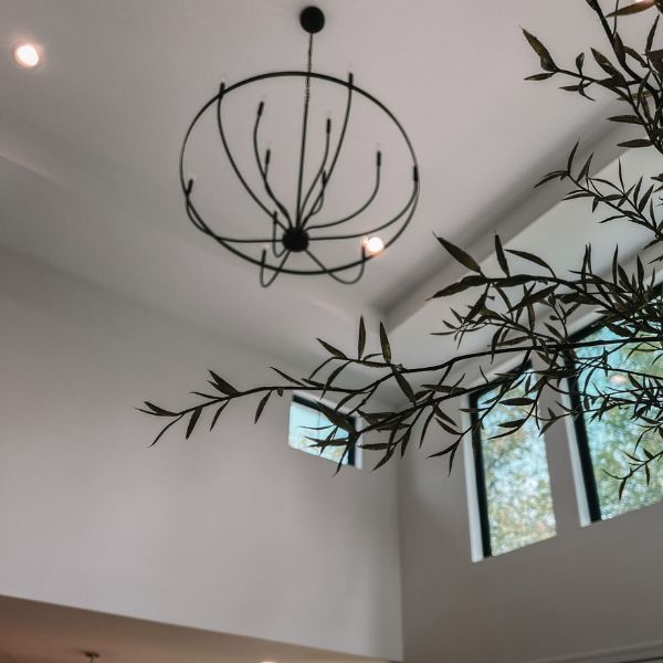 A chandelier hangs from the ceiling above a tree branch