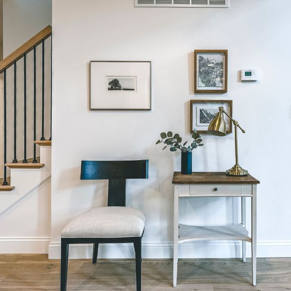 A chair sits next to a table with a lamp on it