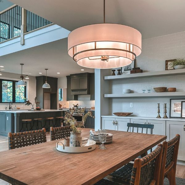 A dining room with a wooden table and chairs and a chandelier hanging from the ceiling.