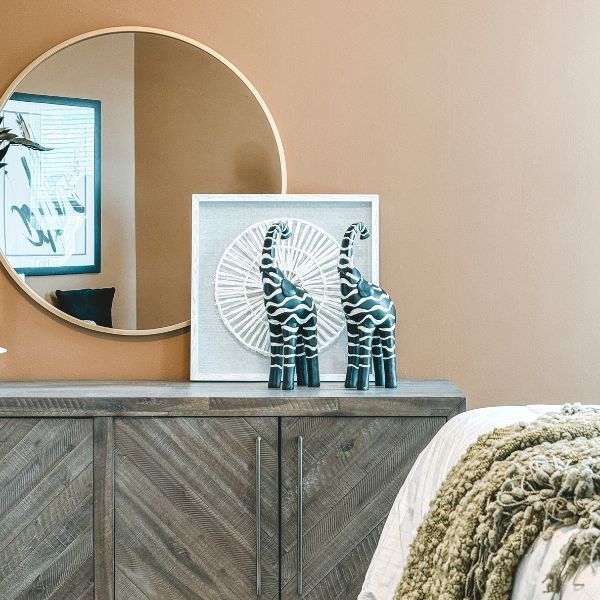 A bedroom with a round mirror and a clock on the wall