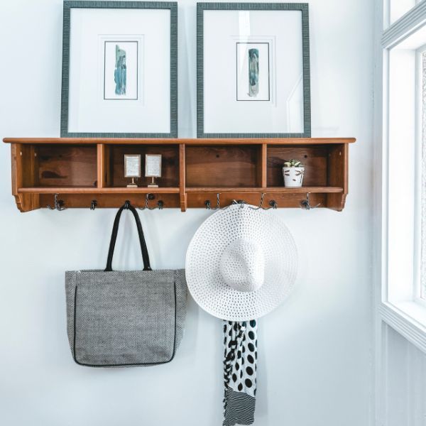 A hat is hanging from a hook on a wooden shelf.