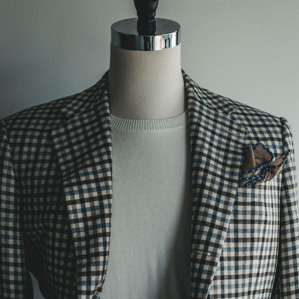 A mannequin is wearing a plaid jacket and a white sweater