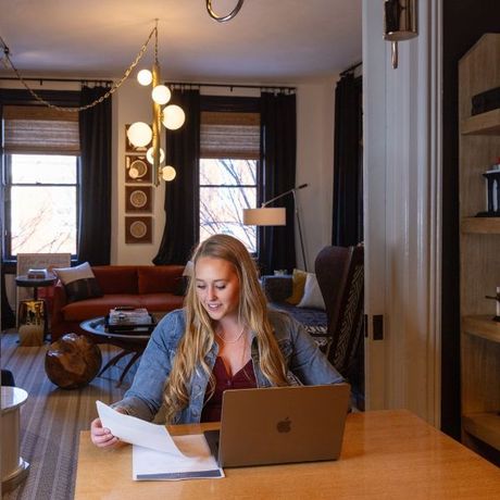 A woman is sitting at a table with an apple laptop