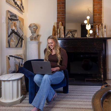 A woman is sitting in a chair using an apple laptop