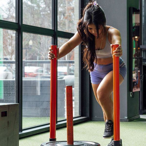 A woman is pushing a sled in a gym