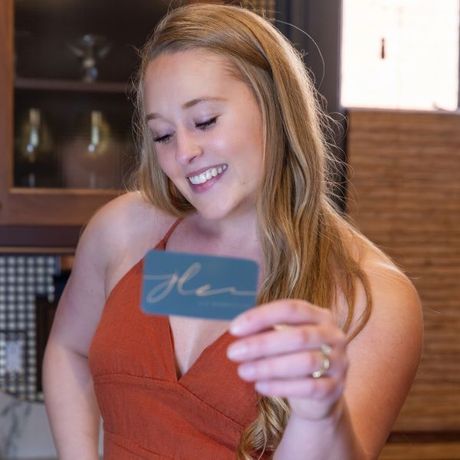 A woman in an orange dress is holding a card that says glen