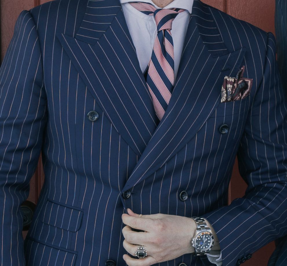 A man wearing a blue striped suit with a pink tie
