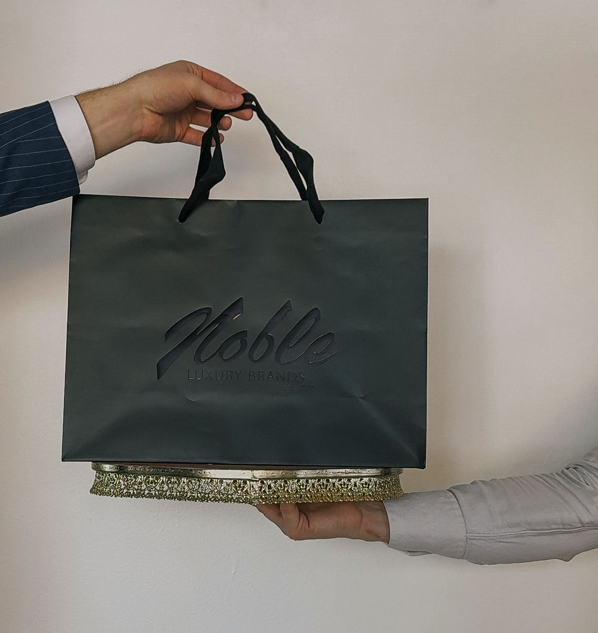 A person is holding a bag that says Noble Luxury Brands