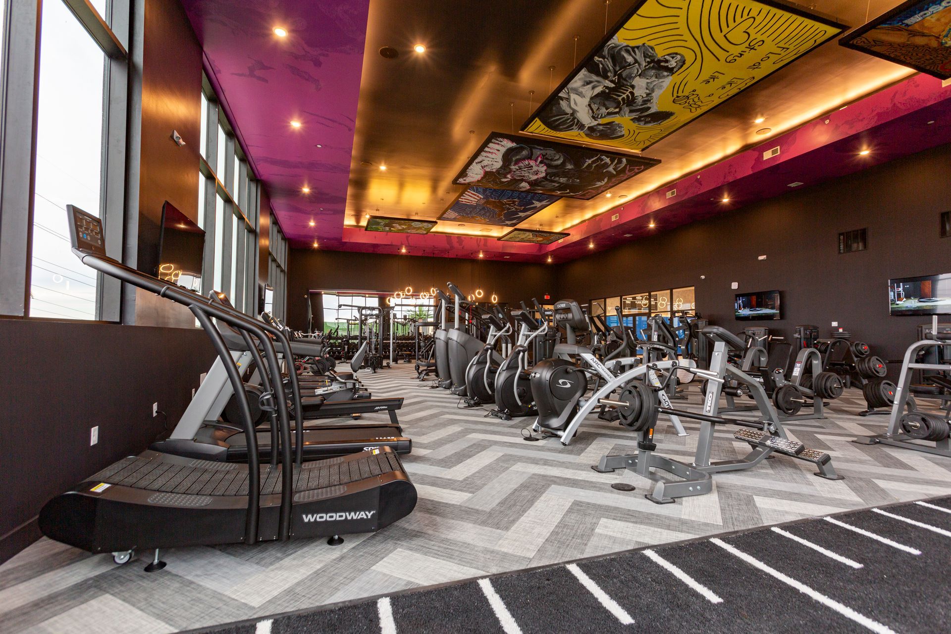 A large gym filled with lots of exercise equipment and a treadmill.