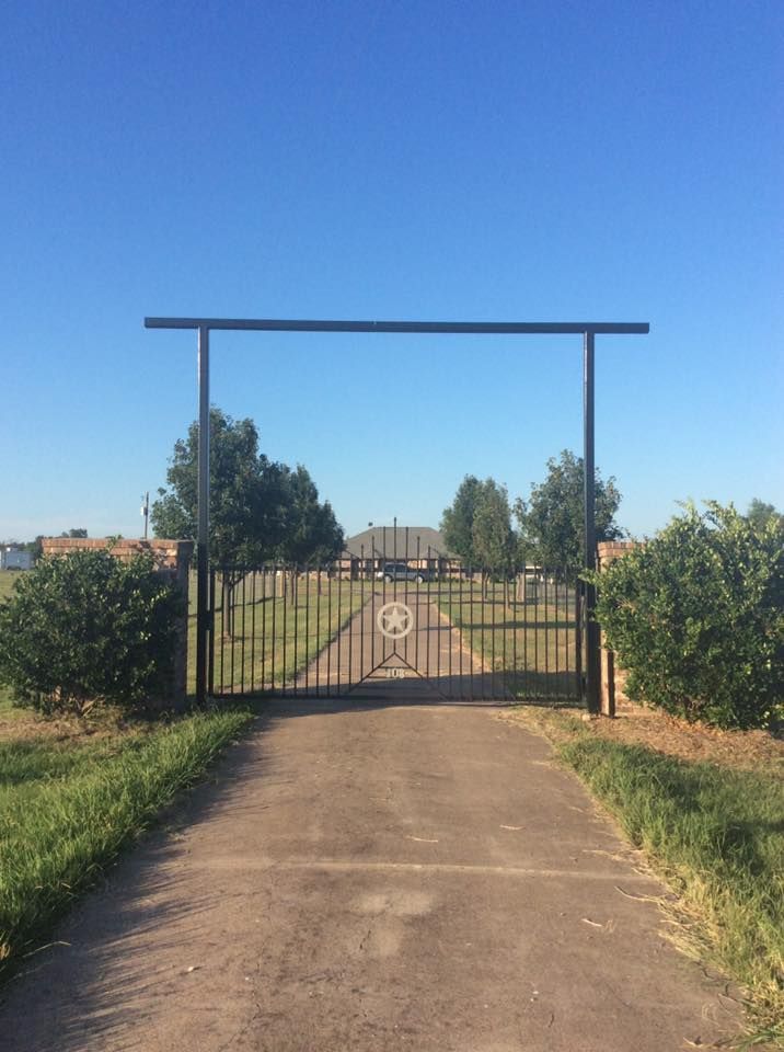 A driveway with a gate that has a circle in the middle of it